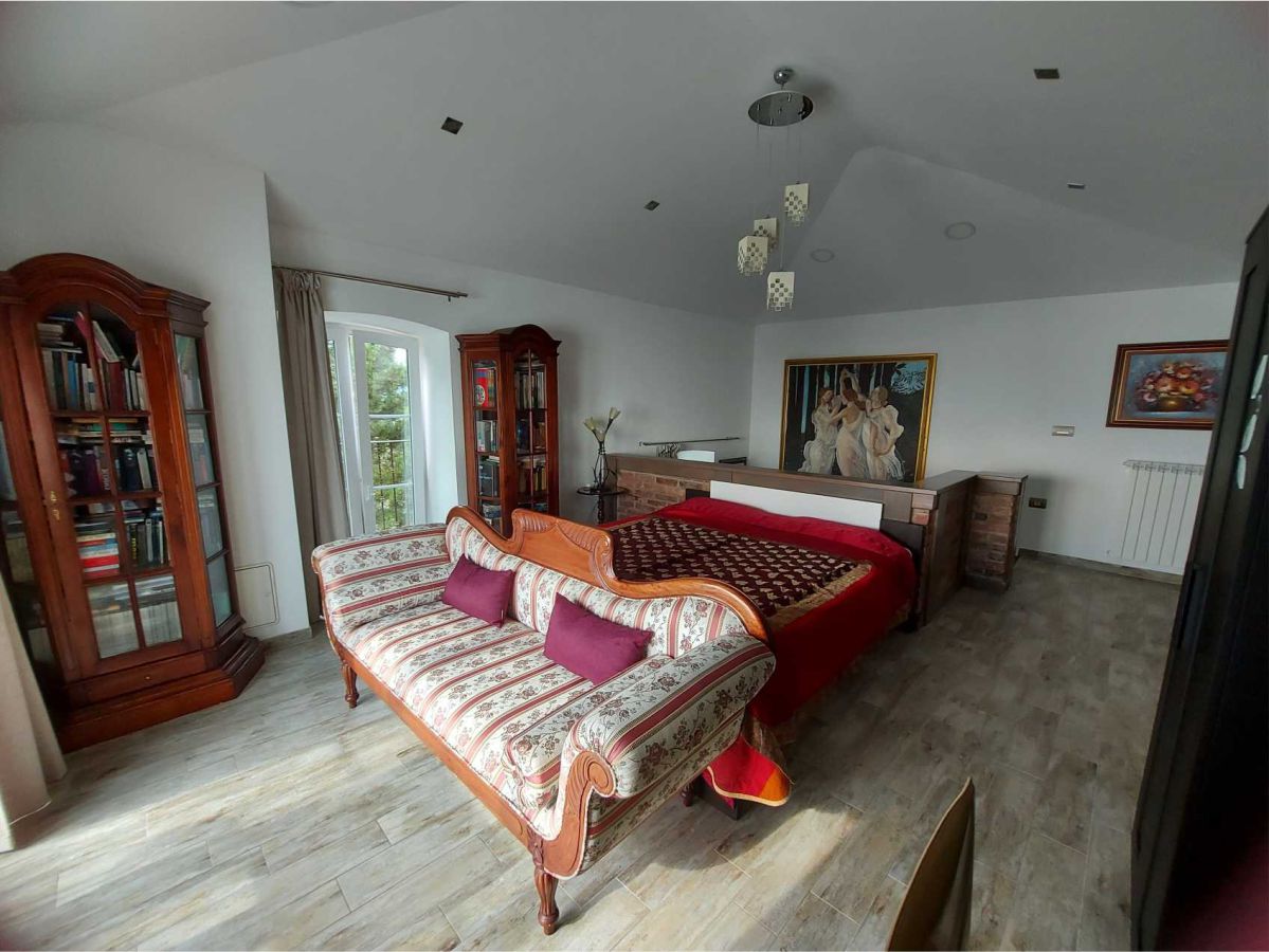 Zwei Kleiderschränke, ein Bett, ein Sofa, ein Kronleuchter an der Decke, ein Fenster, gerahmte Bilder an den Wänden