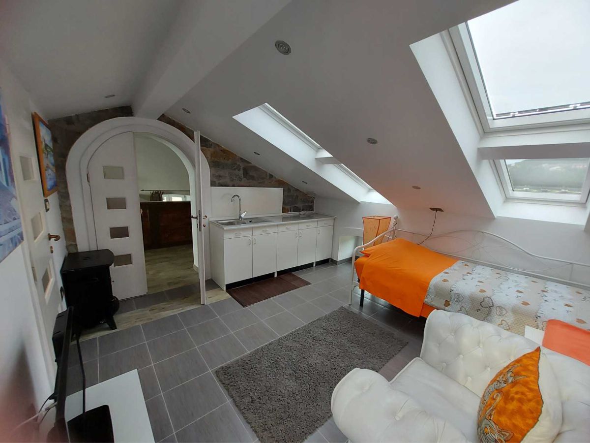 Ein Zimmer mit einem Bett, einer Küchenzeile und Fenstern