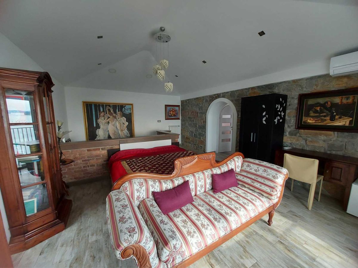 room with a sofa, a bed, wardrobes, behind a brick fence, a large and small painting on the wall, and chandeliers on the ceiling