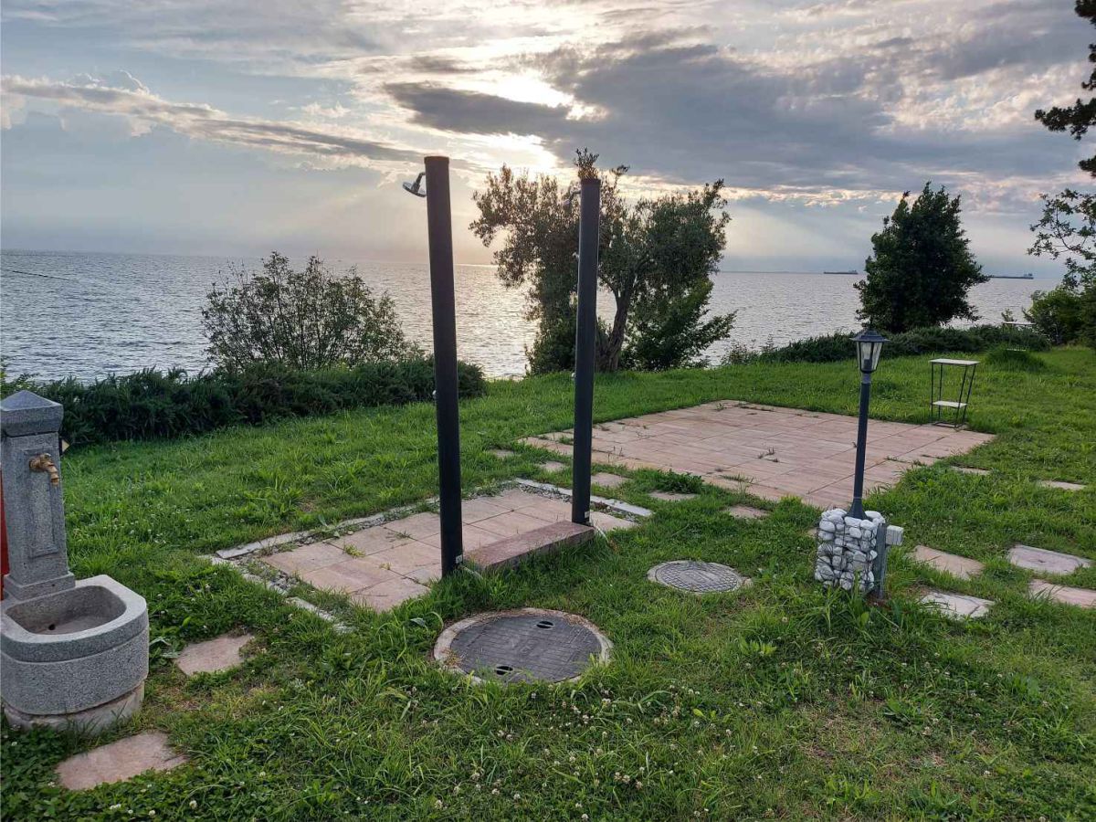 Außendusche, Gartenbeleuchtung, Springbrunnen, Rasenfläche, im Hintergrund Bäume, Büsche und das Meer