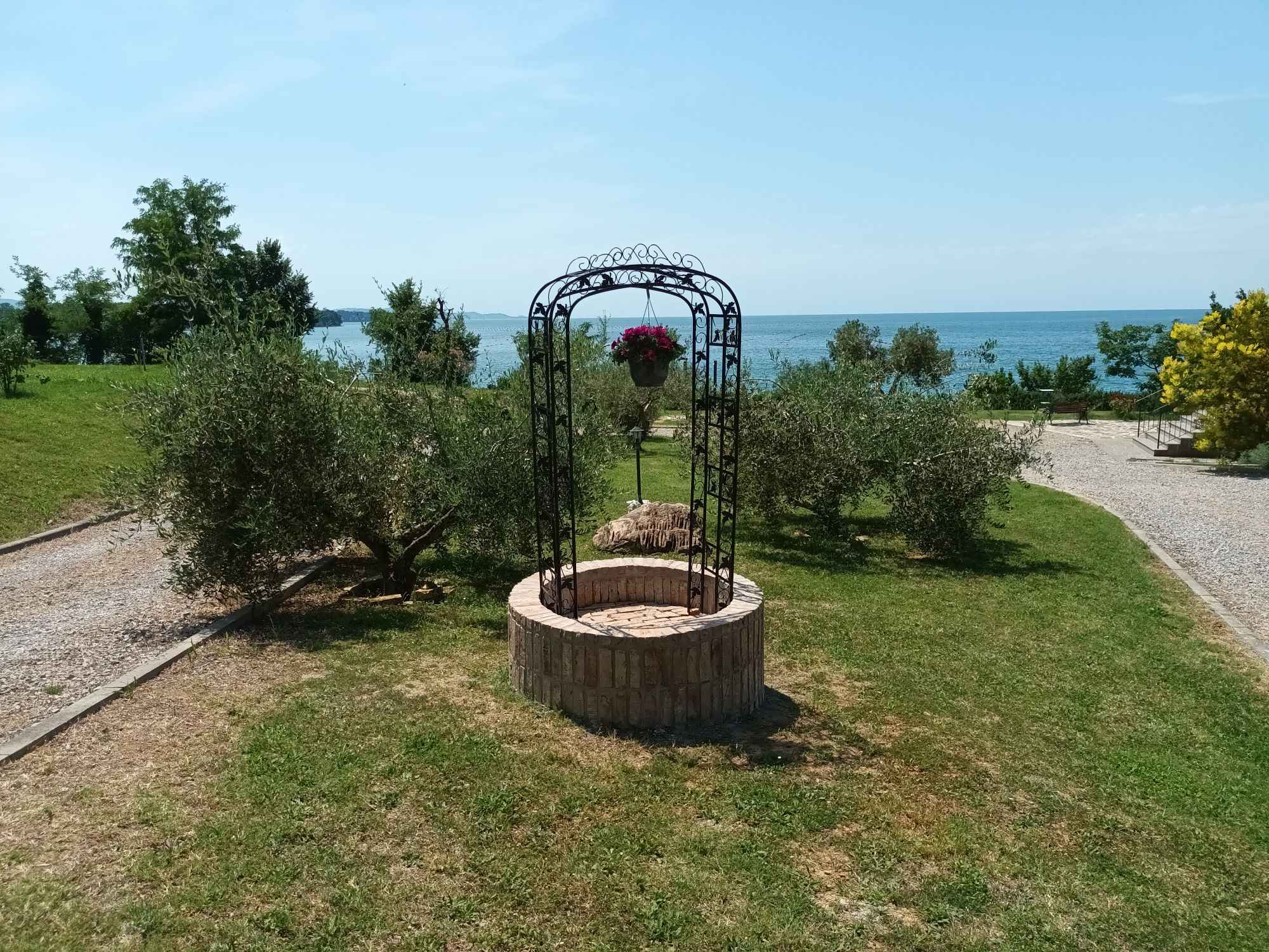 fontana circolare, ulivi, mare sullo sfondo