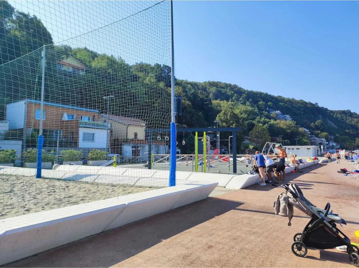 sentiero pavimentato, parchi giochi con sabbia e recinzione in rete, una casa sullo sfondo